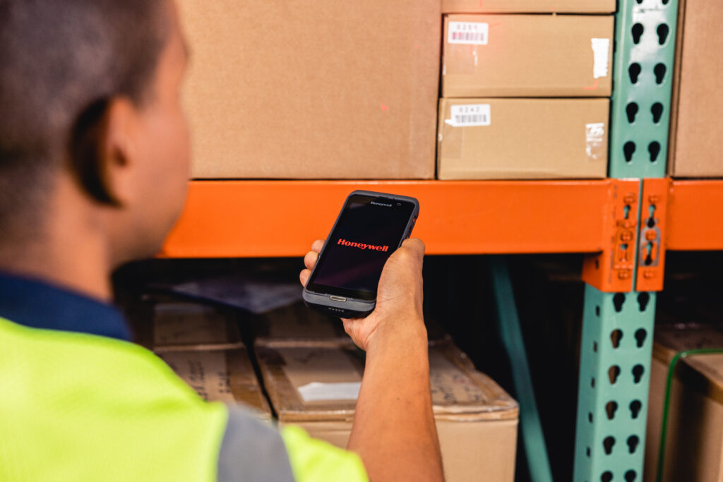 Close up image of warehouse worker using a Honeywell CT47 mobile computer to scan warehouse rack.